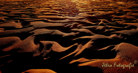 Reliëf van de golven in het zand.