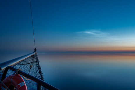 Lichtgevende nachtwolken op zee