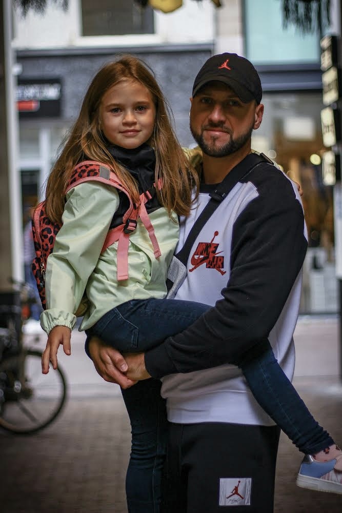 Vader en dochter - Een vader liep met zijn dochter en zijn pas geleden uit Oekraïne gekomen om in Nederland een nieuw hoofdstuk beginnen. De man vroeg om deze reden of  - foto door Chesronfoto97 op 20-09-2023 - locatie: Den Haag, Nederland - deze foto bevat: vader, dochter, samen, den haag, mode, textiel, geel, brillen, kap, weg, baseball pet, plezier, evenement, stad
