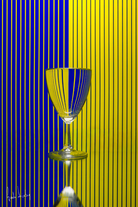 Glas tegen blauw gele gelijnde achtergrond