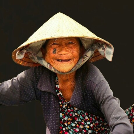 Straat portret.: Oude vietnamese verkoopster in een roeiboot