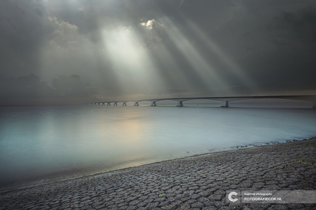 Zonnestralen boven de Zeelandbrug en de Oosterschelde