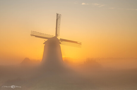 Molen bij mistige zonsopkomst