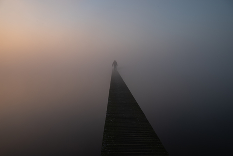 Een vlonderpad wat verdwijnt in de mist