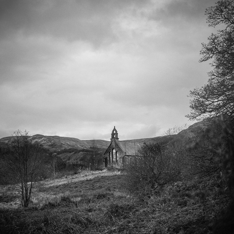 Vervallen kerkje met een paar grafstenen.