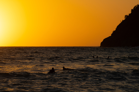 Surfers bij zonsondergang