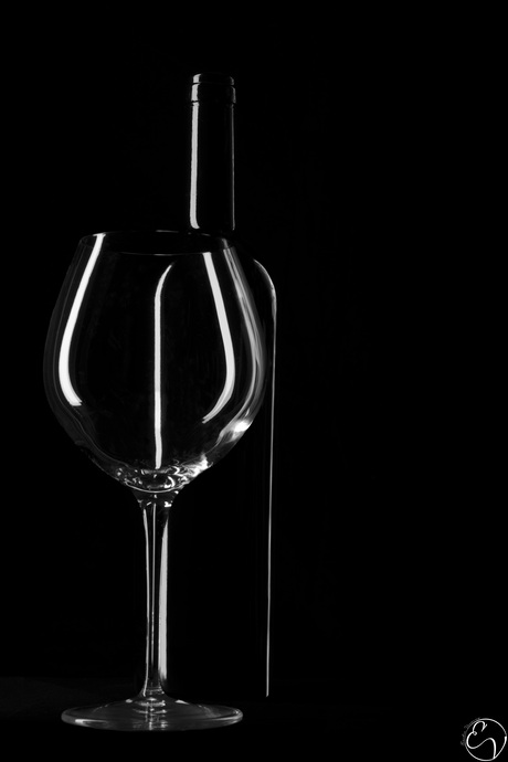 Wijnglas en -fles tegen zwarte achtergrond