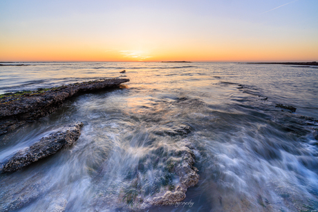 Zonsondergang aan de Opaalkust met beweging in de zee.