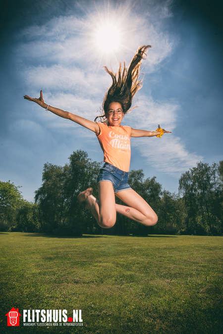 Spring in 't veld - 
Volgend schooljaar gaat onze dochter naar de middelbare school. Ze moet een werkstuk over haar zelf maken en één van de opdrachten luidt, "een foto  - foto door Provorm op 10-06-2021 - locatie: Amersfoort, Nederland - deze foto bevat: meisje, haar, flits, flitser, strobist, flitshuis, blauw, groen, oranje, springen, korte broek, zon, tegenlicht, kleurrijk, blij, vrolijk, dansen, wild, lucht, wolk, fabriek, mensen in de natuur, menselijk lichaam, flitsfotografie, boom, gelukkig, gras, gebaar